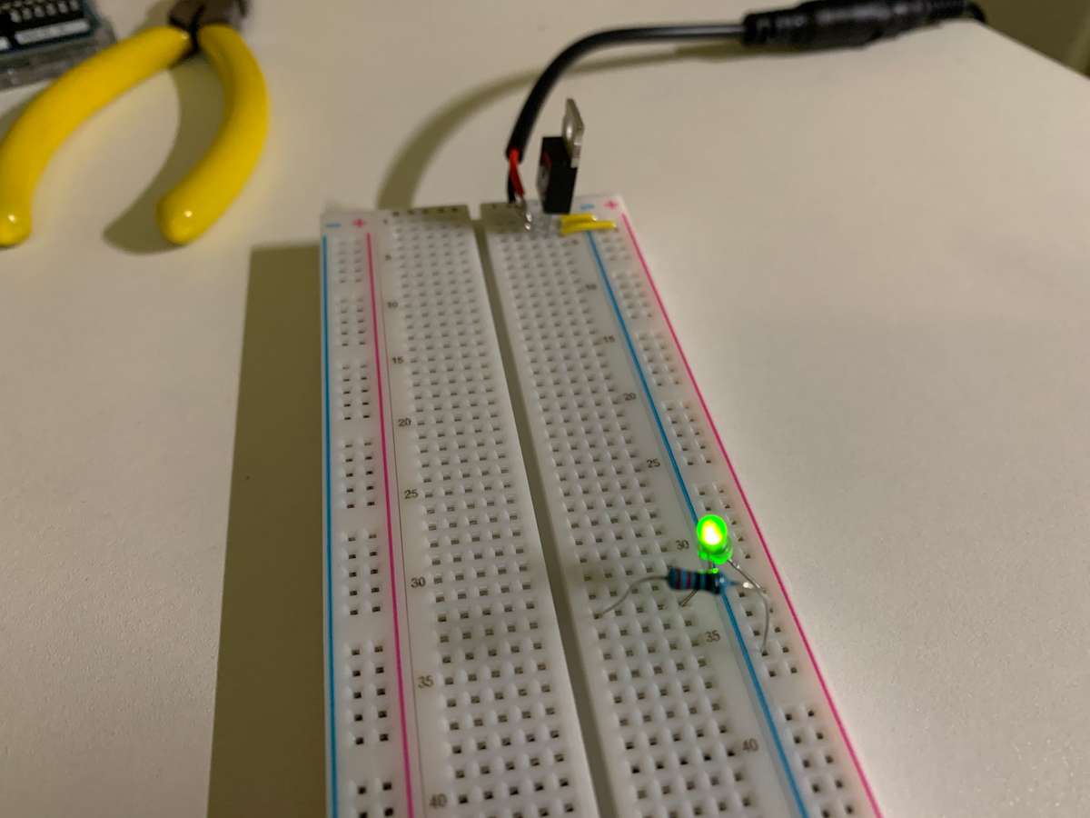 Breadboard with a LM7805 5V voltage regulator and a glowing green LED